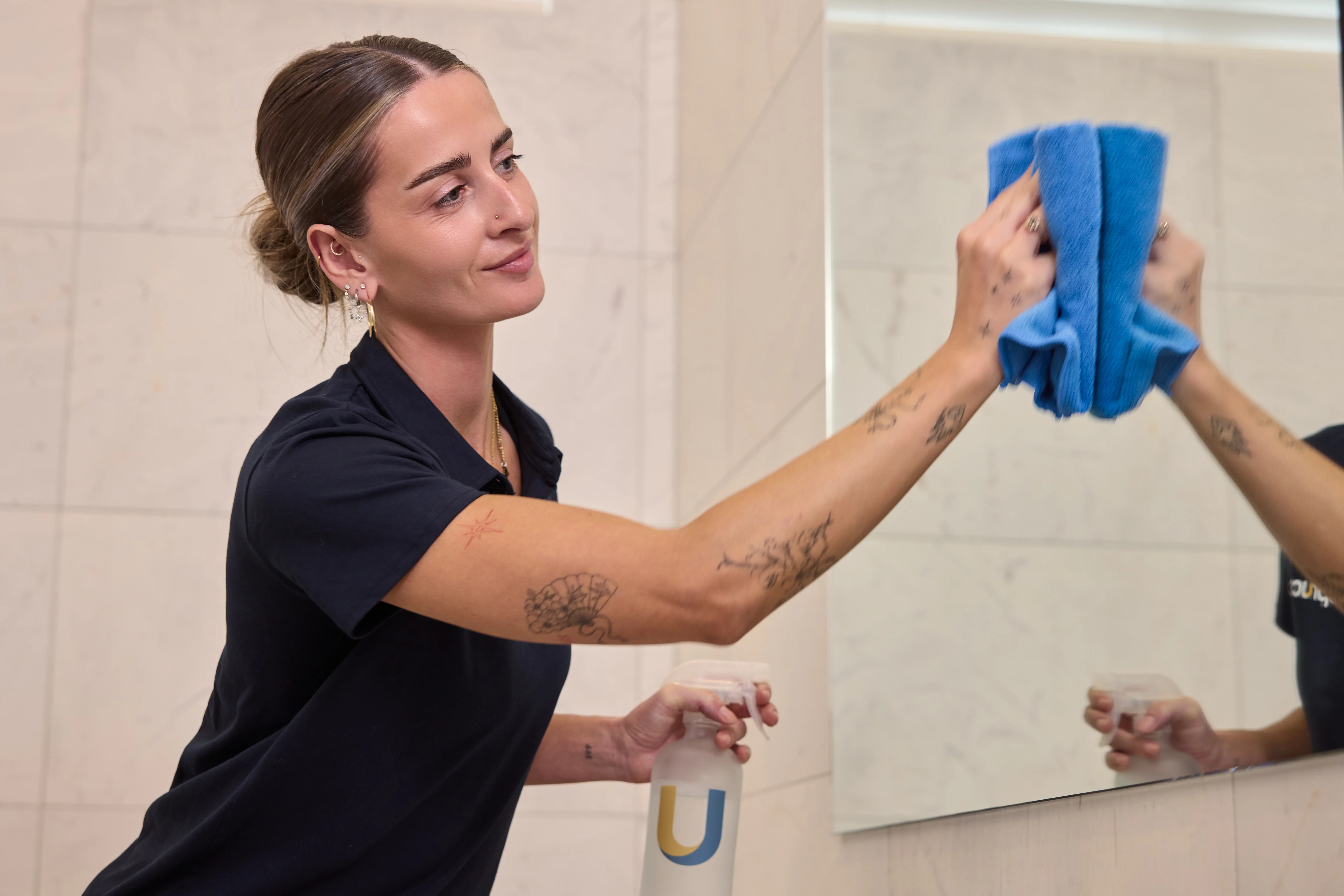 A Spruce cleaner wiping a bathroom mirror during an end-of-tenancy clean in an Auckland home