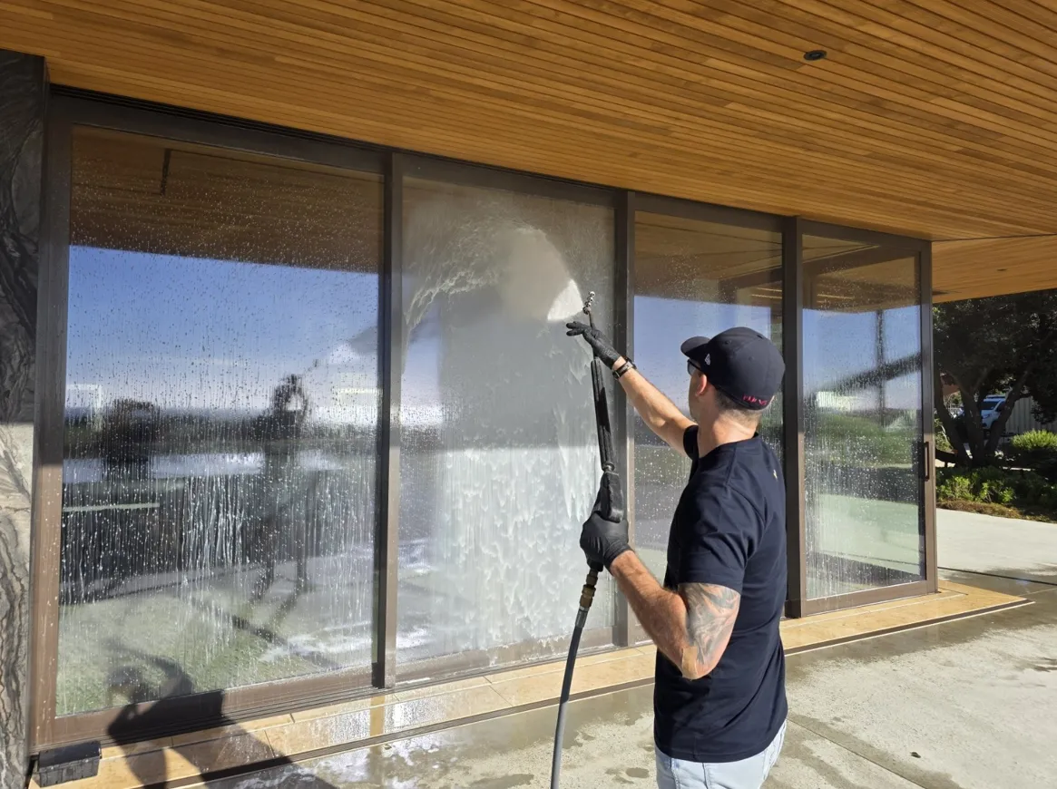 A Spruce technician soft-washing the exterior glass and joinery of a New Zealand home
