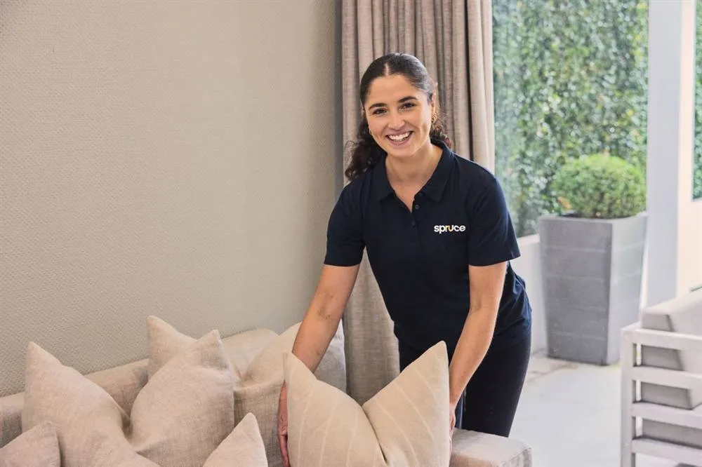 A Spruce cleaner plumping cushions in a Hamilton living room