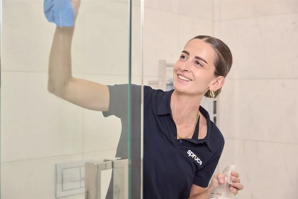 Spruce cleaner polishing a shower glass panel