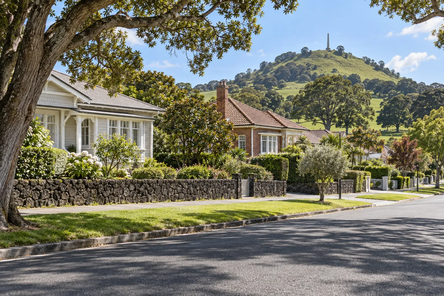 Bungalows and volcanic-stone garden walls on a One Tree Hill street below Maungakiekie