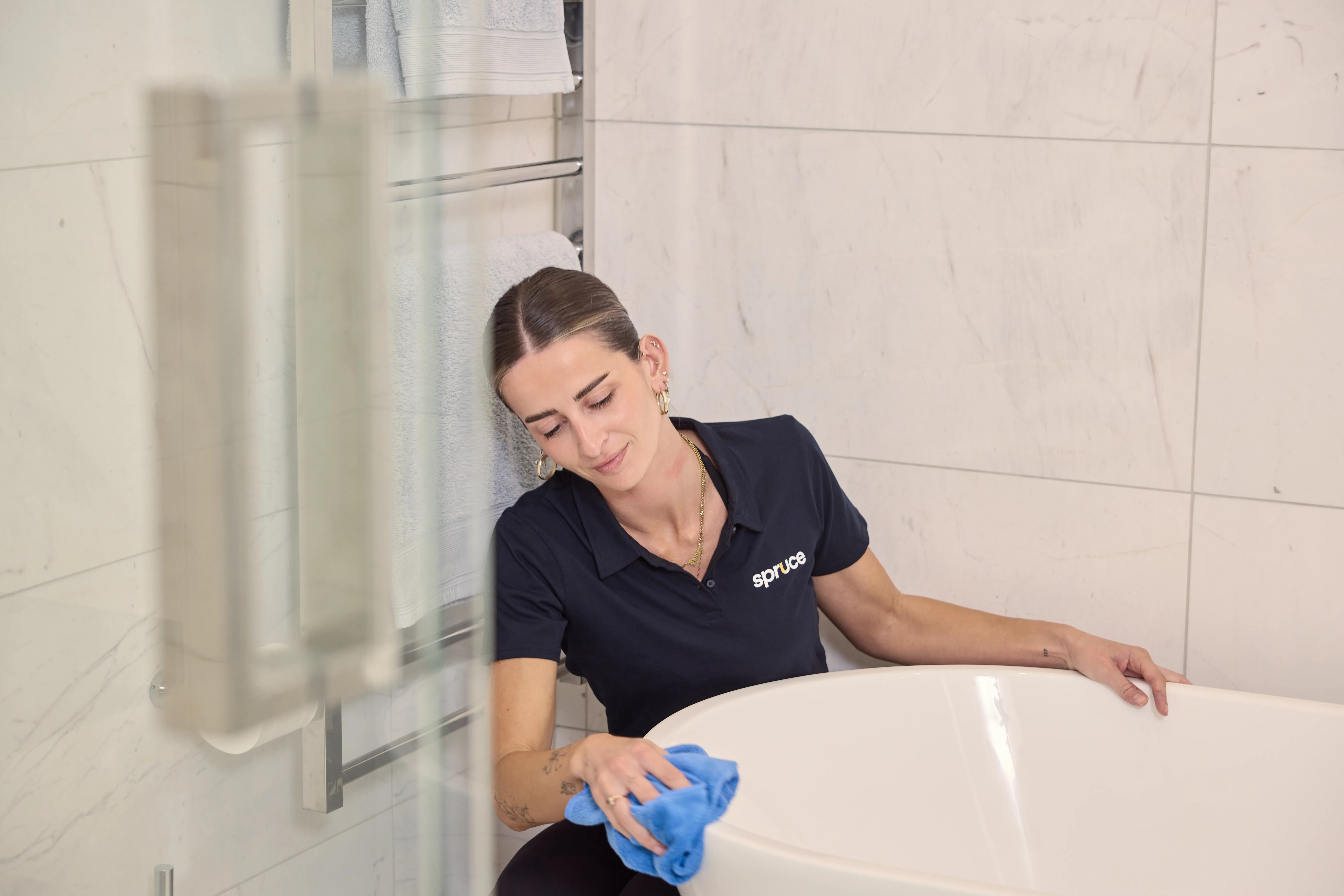 A Spruce cleaner wiping a bathtub during a regular clean in an Auckland home