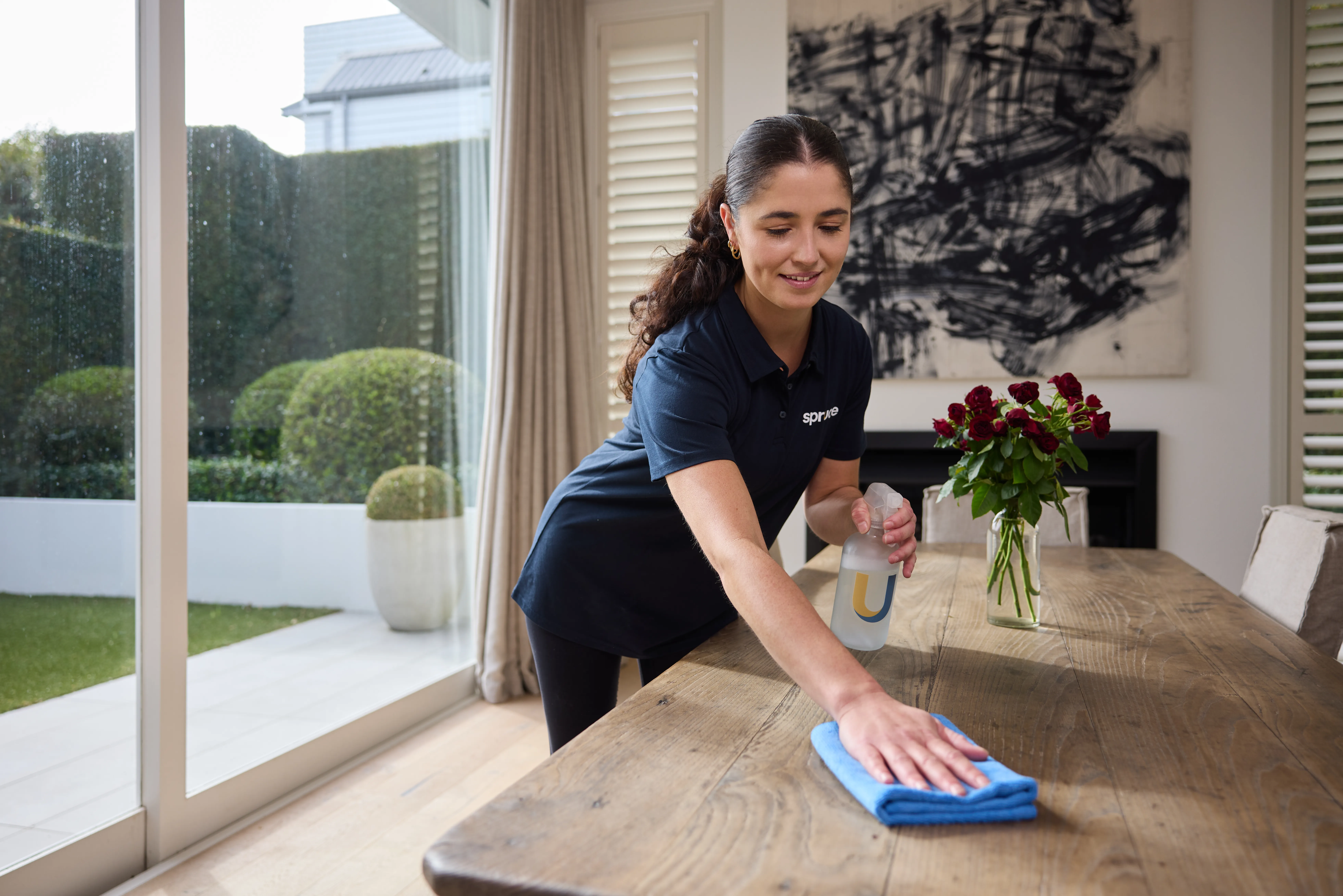 A Spruce cleaner wiping a dining table during a regular clean in a Wellington home