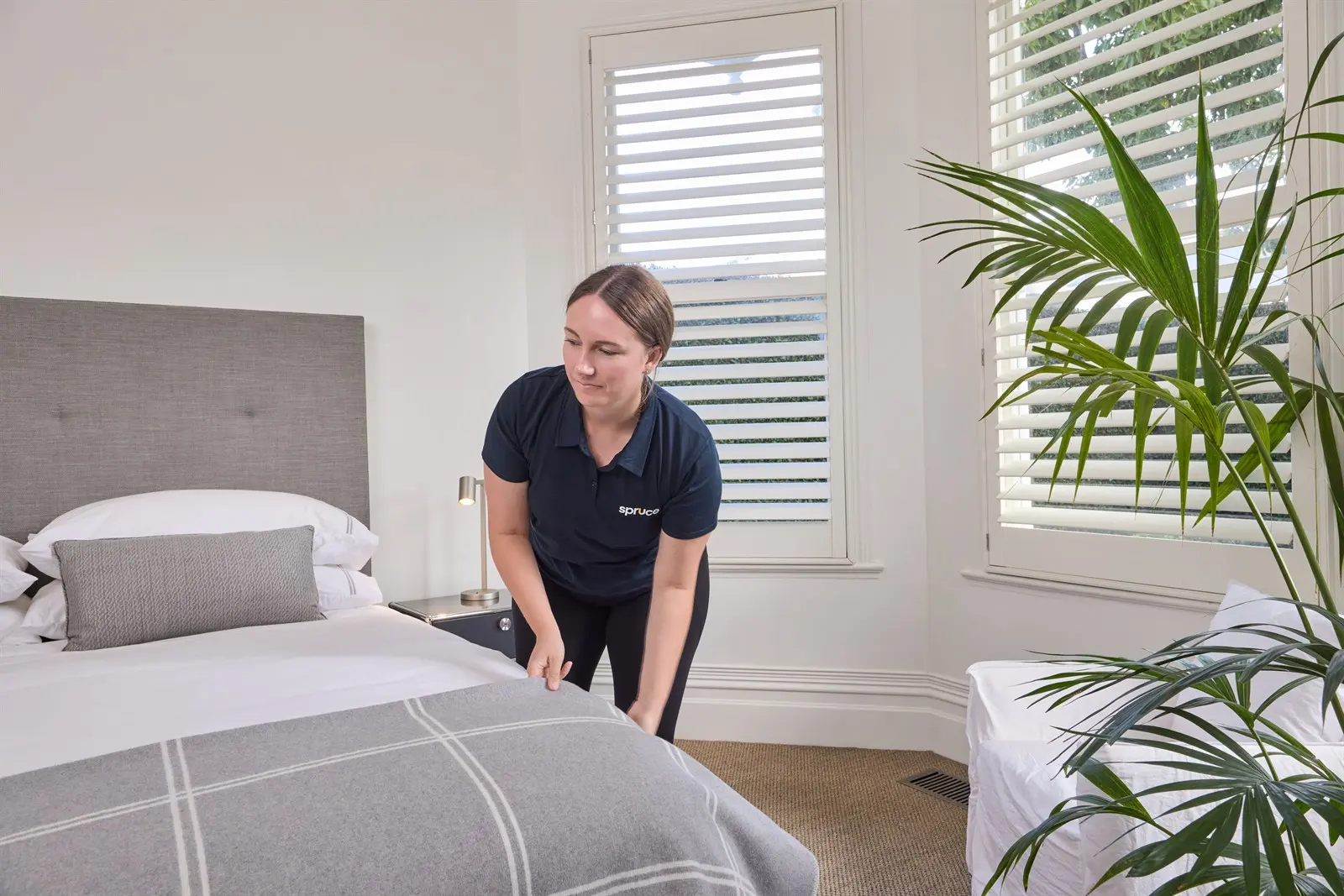 A Spruce cleaner making a bed in a New Zealand bedroom