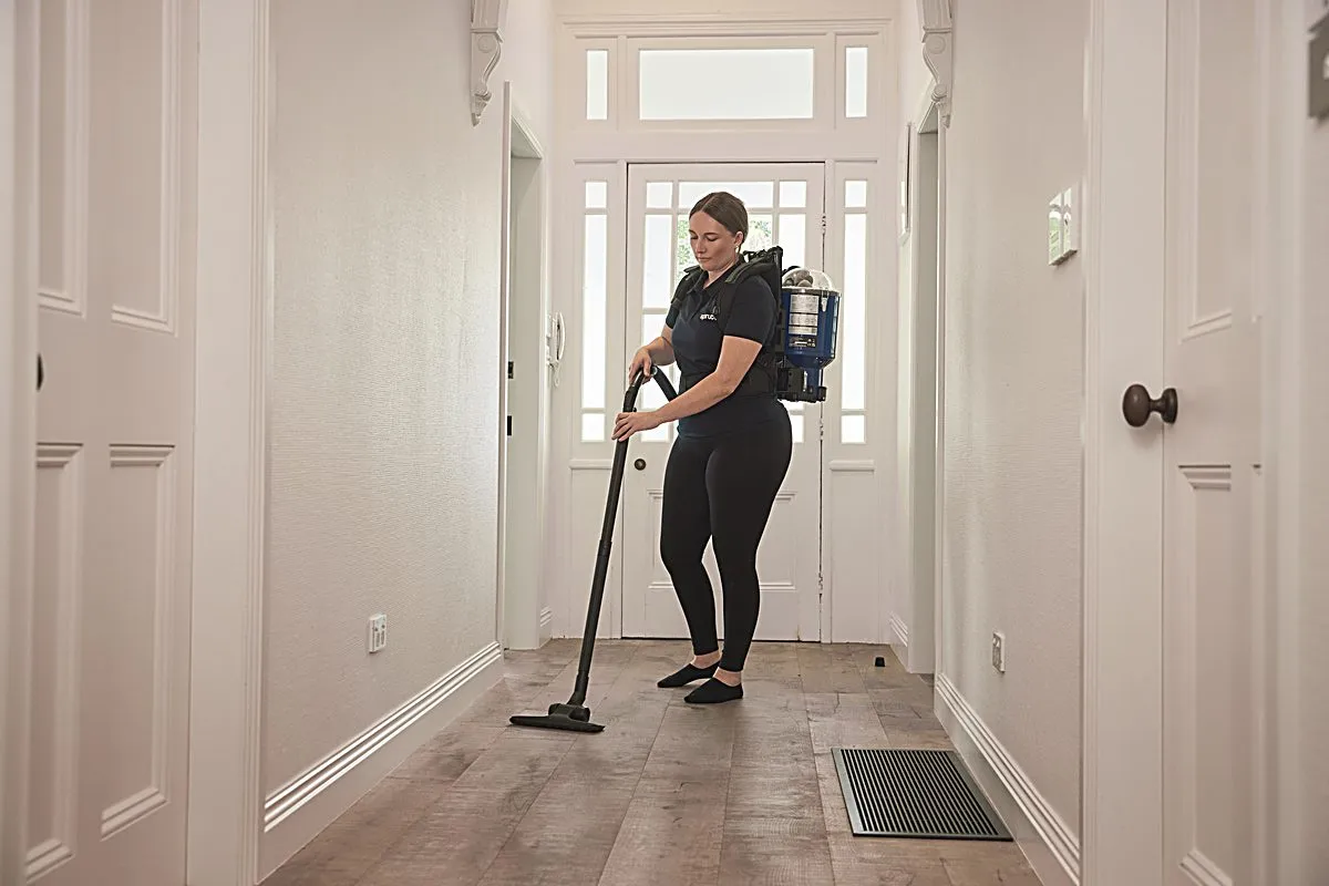 A Spruce cleaner vacuuming the floor of a bright New Zealand living room