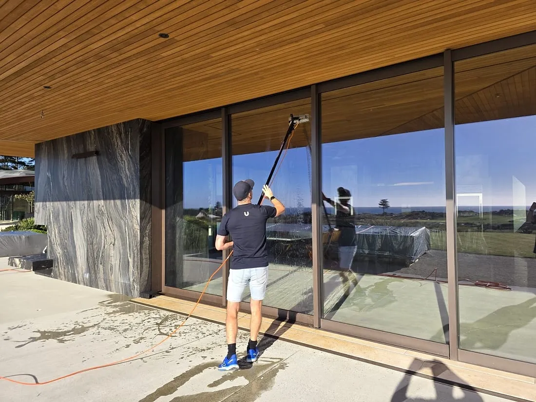 A Spruce technician washing large picture windows with a pure-water pole at a Wellington home