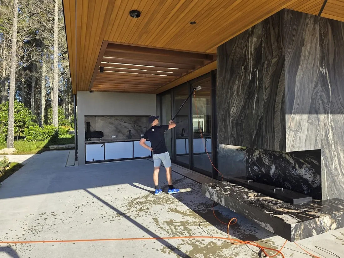 A Spruce technician reaching high glass with a pure-water pole at a Wellington home